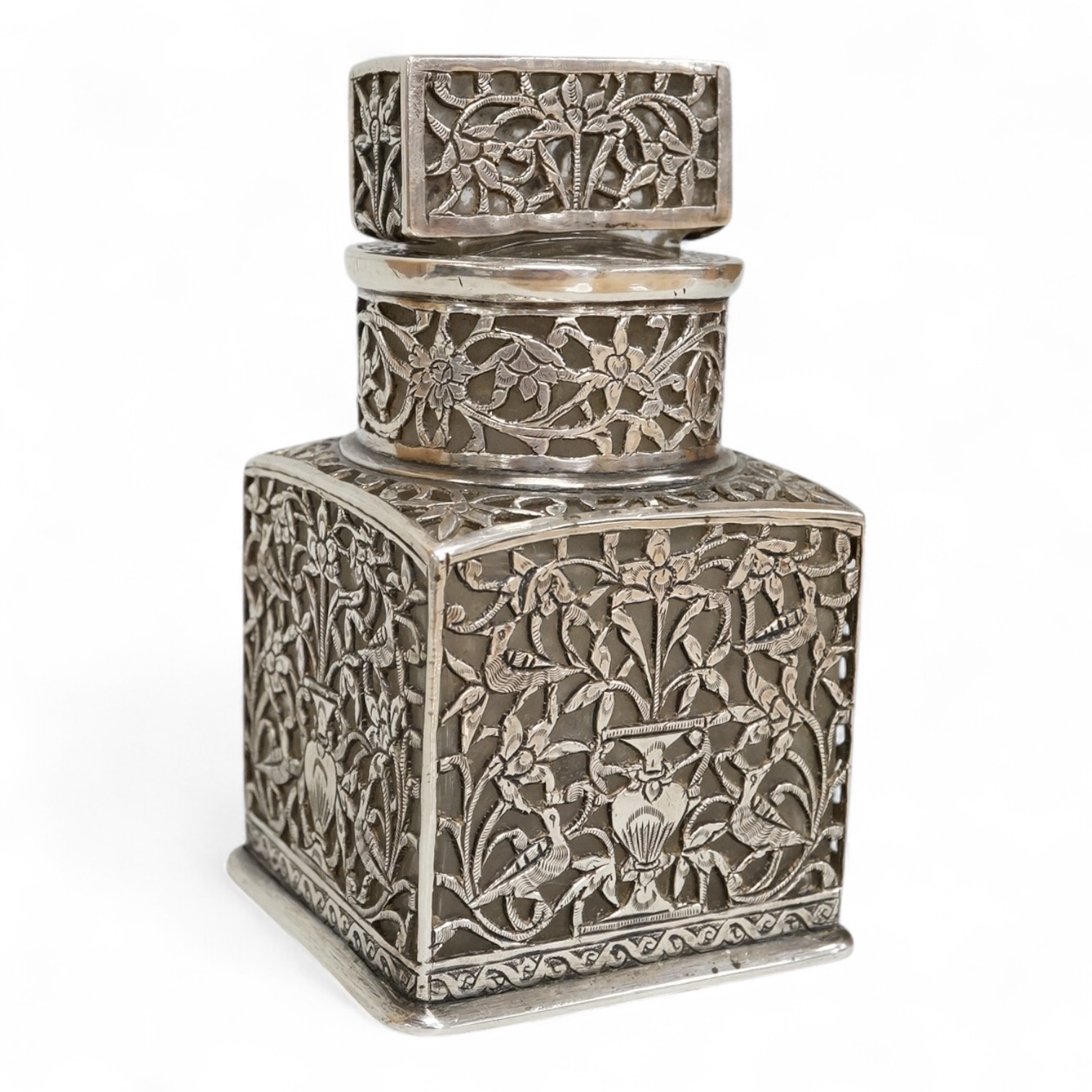A Persian pierced white metal overlaid moulded glass salts bottle with stopper, decorated with urns and birds amid scrolling foliage, overall height 94mm.